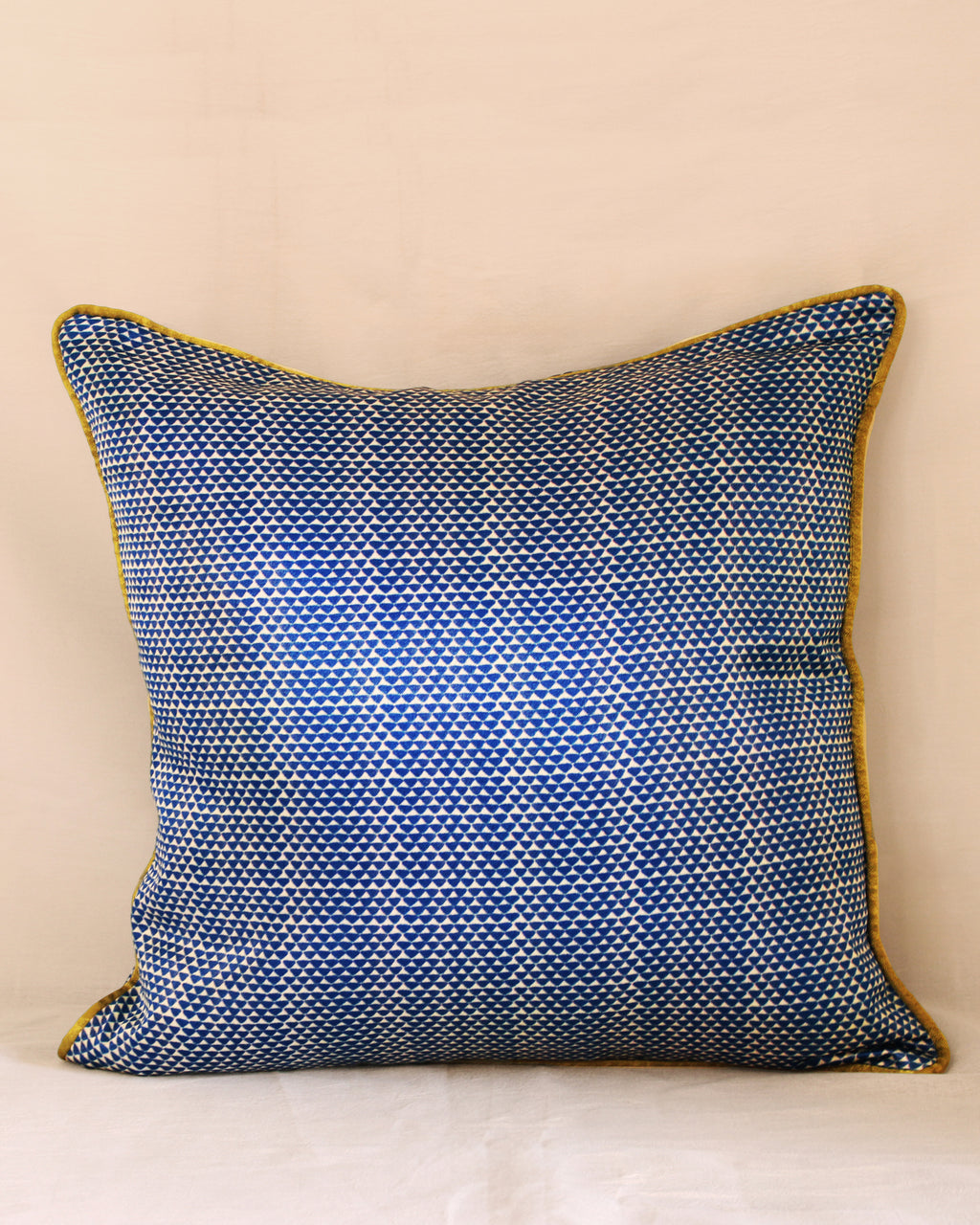 Blue patterned pillow with yellow trim on a beige background