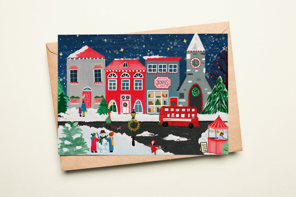 Christmas-themed card with a winter village scene and envelope on a night background