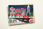 Christmas-themed card with a winter village scene and envelope on a night background
