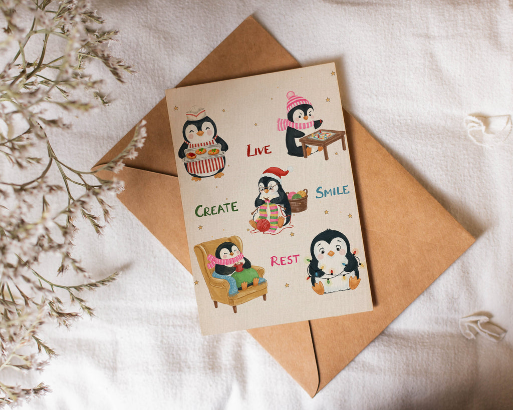 Card with penguin illustrations and envelope on a white fabric background