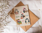 Card with penguin illustrations and envelope on a white fabric background
