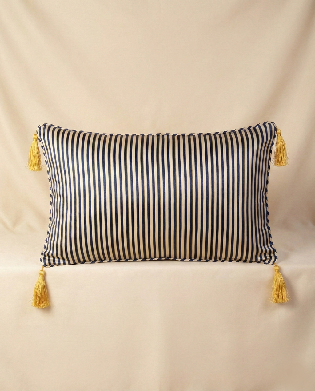 Navy striped pillow with yellow tassels on a beige background