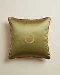 Green pillow with a gold emblem on a beige background