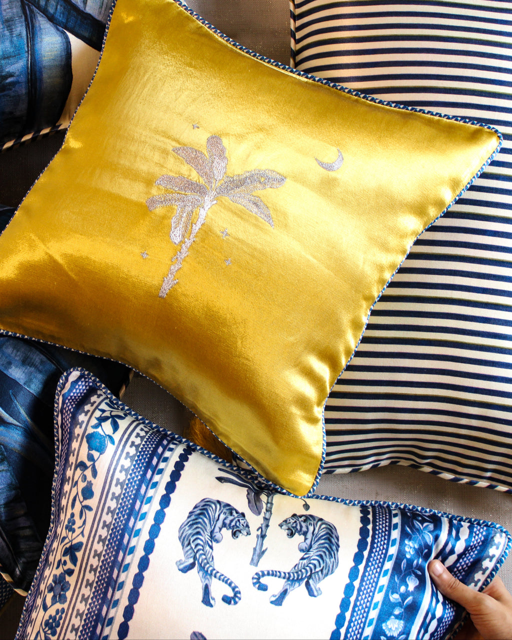 Collection of decorative pillows with a yellow pillow featuring a palm tree design.