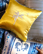 Collection of decorative pillows with a yellow pillow featuring a palm tree design.