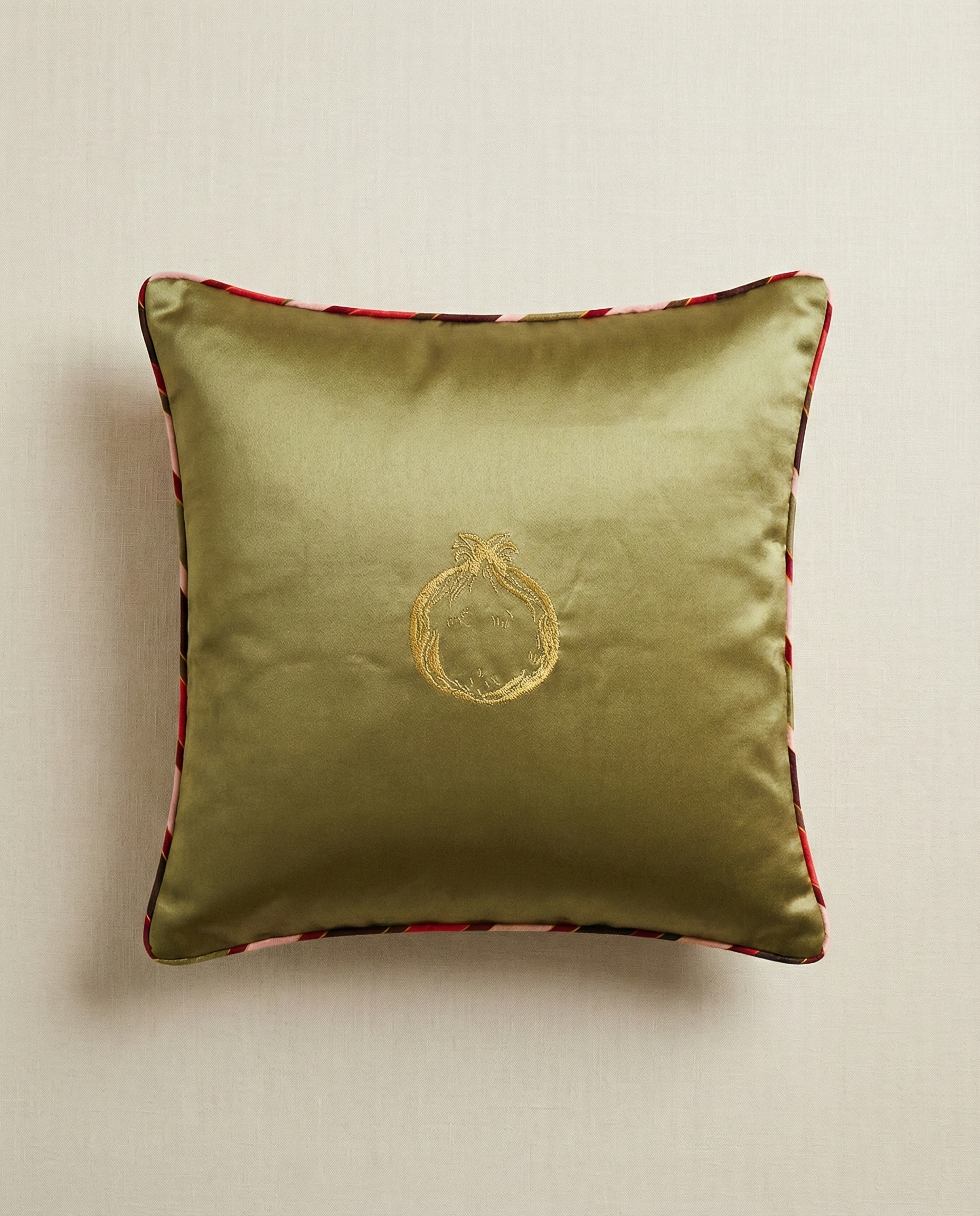 Green pillow with a gold emblem on a beige background
