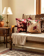 Decorative cushions on a wooden bench with a lamp and plant in the background
