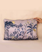 Decorative pillow with nature-themed design held by a hand against a plain background