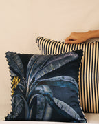 Two decorative pillows, one with a leaf pattern and one with a striped design, on a beige sofa.