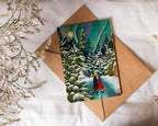 Greeting card with a winter scene of a couple  in a red coat standing in a snowy landscape, placed on a brown envelope with a white background.