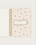 Floral patterned notebook with gold spiral binding on a white background