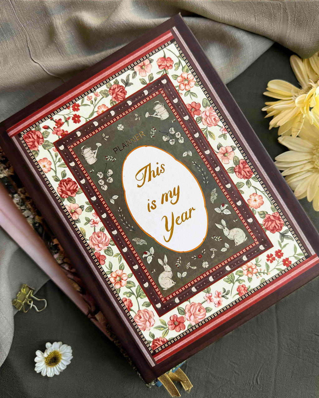 Decorative planner with floral design and 'This is my Year' text on a gray surface with flowers.
