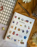 Notebook with small illustration on a textured surface with flowers and a pen.